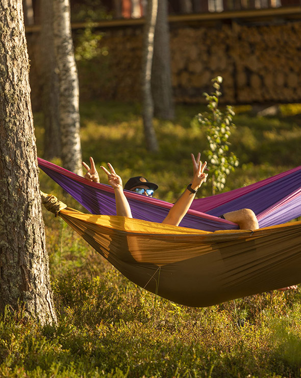 Kaksi henkilö värikkäissä riippumatoissa.