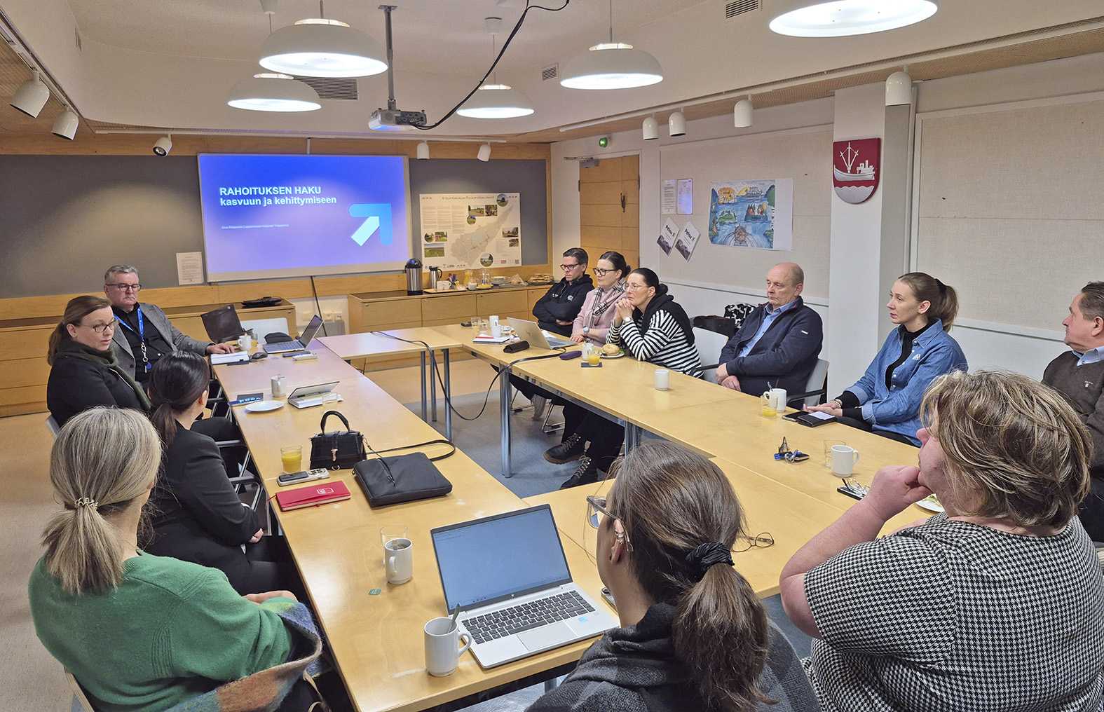 Pöydän ympärillä istuu henkilöitä.